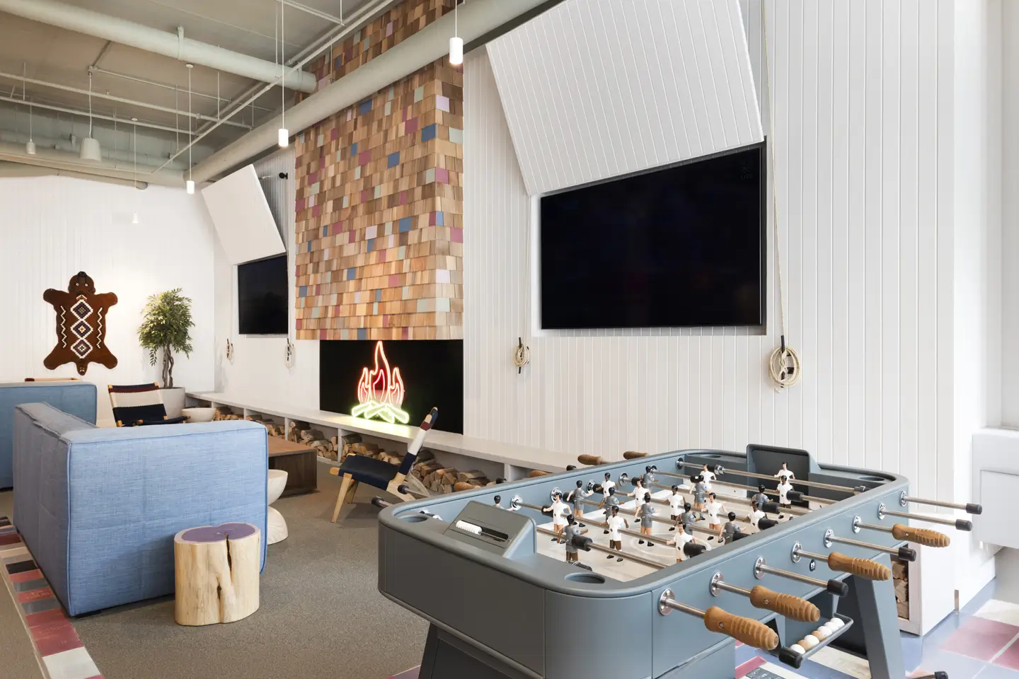 Apartment lobby featuring a fake fireplace, a mounted flat screen TV, and a foosball table.